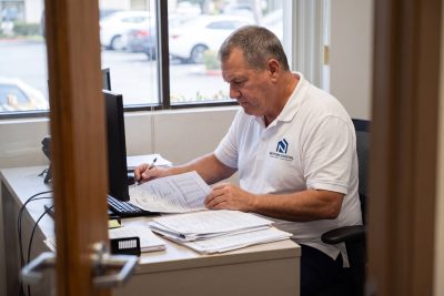 NextGen Coastal property manager reviewing a three-day notice and lease at a Costa Mesa office desk