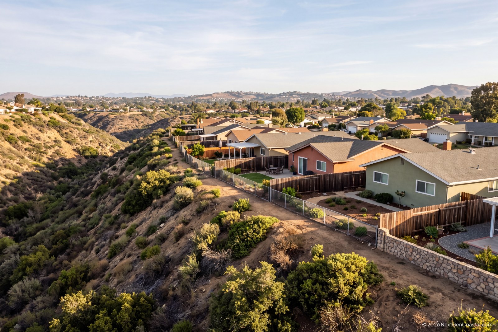Ranch-style rental homes on a San Diego canyon rim with cleared brush management zone behind the fences