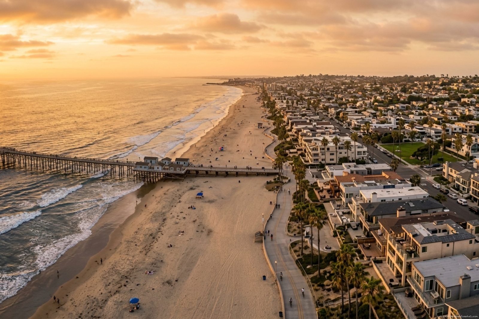 Aerial view of San Diego's Pacific Beach coastline at golden hour, showing beachfront residential properties along the shore with waves breaking on sandy beach