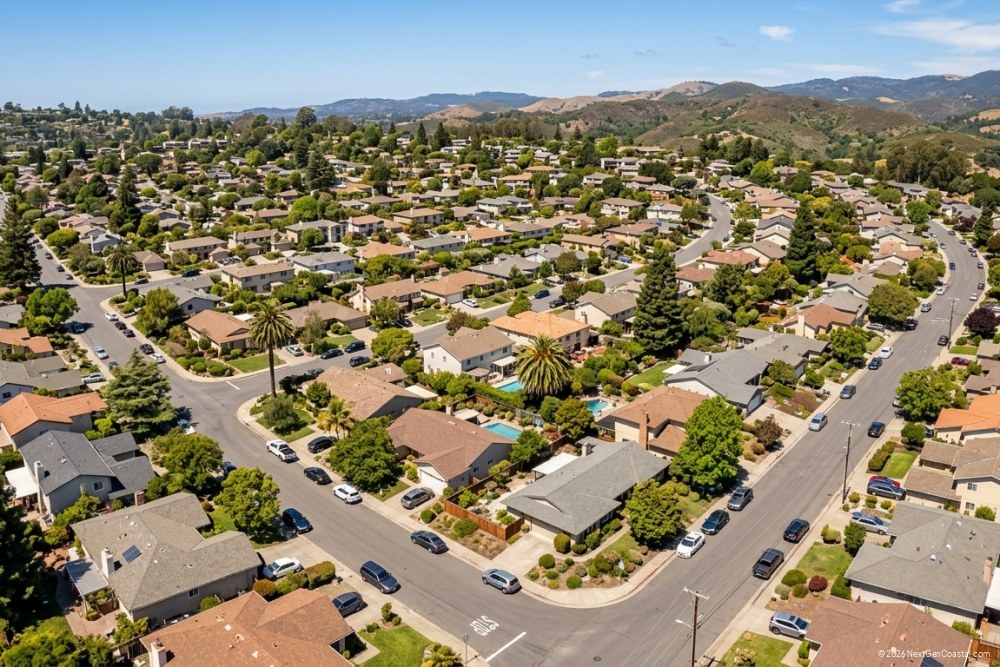 Photorealistic DSLR photograph of a coastal California residential neighborhood from an elevated perspective, mix of single-family homes and low-rise condos, tree-lined streets, no ocean visible, suburban density, mid-afternoon natural light