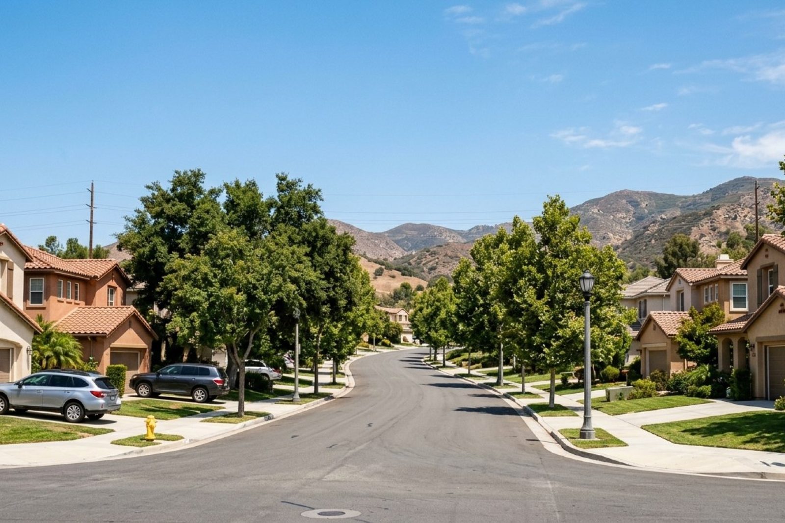 Photorealistic DSLR photograph of a hillside California residential street with mature trees and modern single-family homes under clear afternoon light, no ocean visible, inland suburban setting