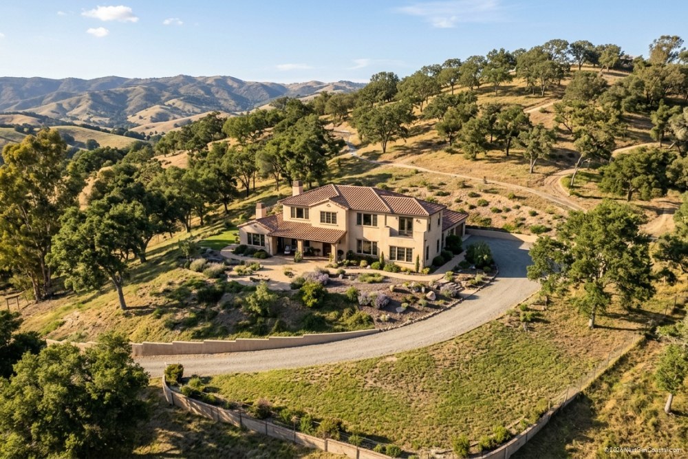 California hillside single-family home with cleared defensible space zones, mature trees thinned, and visible brush clearance around the structure under afternoon light